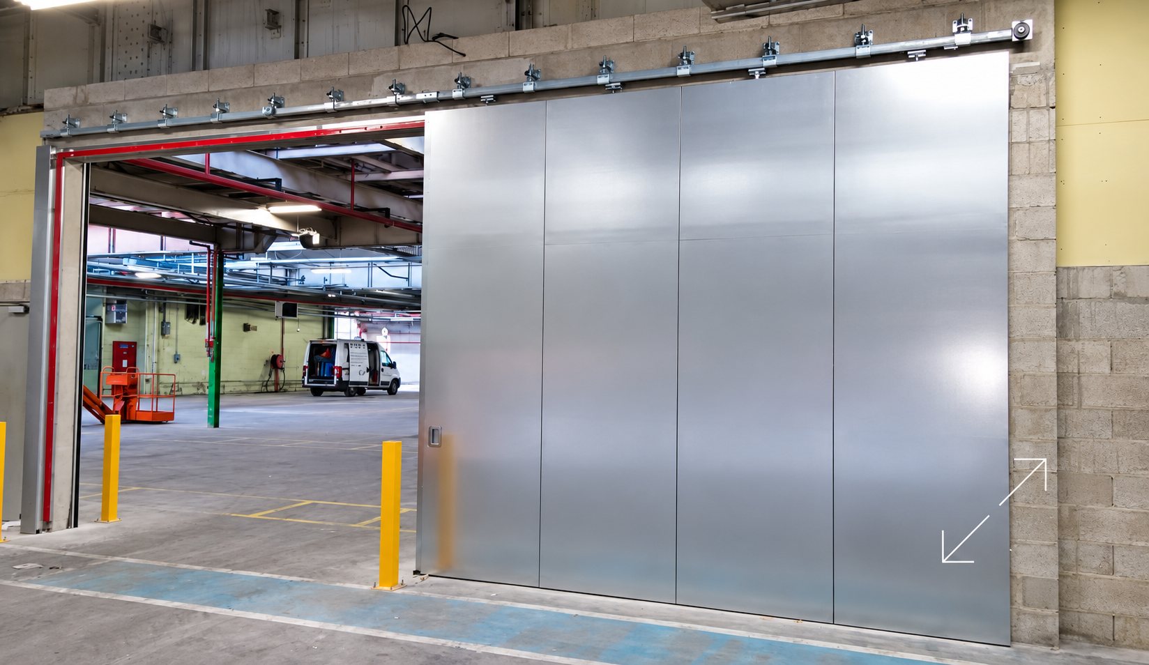 Une grande porte coulissante en métal galvanisé sur rail, posée dans un mur de parpaings, ouvre sur un entrepôt où stationne une camionnette blanche.